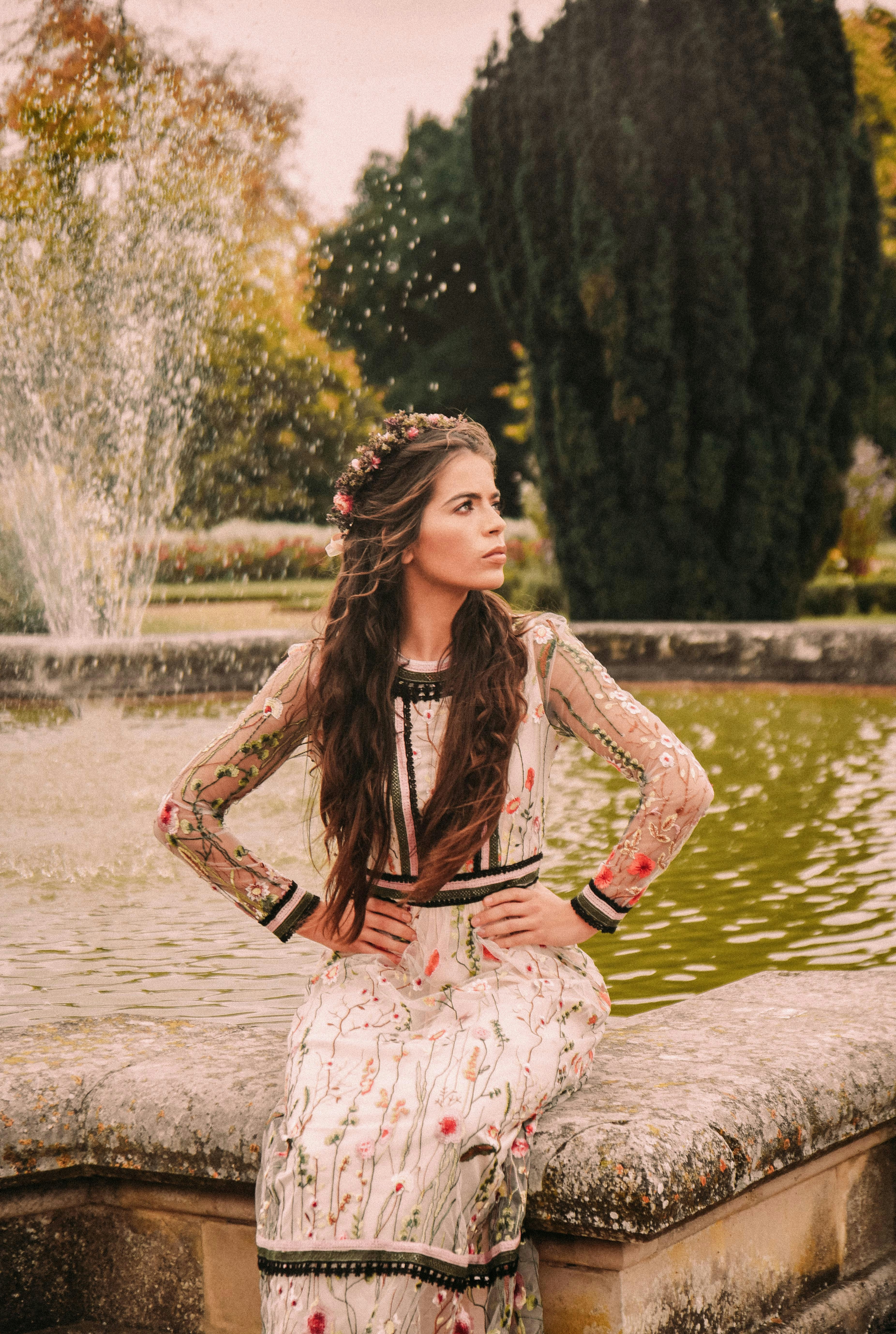 woman sitting on water fountain at daytime